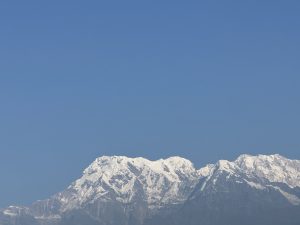 A panoramic view of a majestic mountain range under a clear blue sky. 