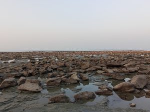A rocky coastal shore with large stones and shallow water at Saint Martin, Bangladesh.
