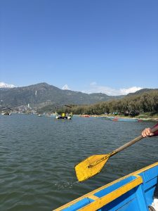 A serene lakeside scene featuring a wooden boat with a bright blue and yellow design.