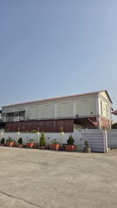 A large, two-story building with a mix of yellow and red brick exteriors is shown against a clear blue sky