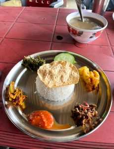 
A stainless steel plate contains a serving of white rice topped with a crispy papadum.