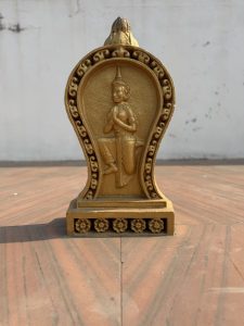 A golden decorative statue featuring a figure in a traditional pose, possibly representing a deity or cultural icon. 
