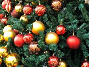 A Christmas tree with lots of large gold and red ball ornaments hanging from it.