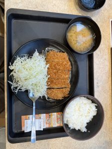 Japanese-style meal tray with breaded cutlet, shredded cabbage, rice, and miso soup.