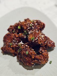 Crispy Korean fried chicken pieces coated in a rich, glossy sauce and topped with sesame seeds in Kozhikode, Kerala, look hot, spicy, and appetising.