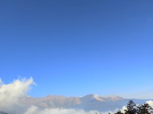 
A clear blue sky with a few wispy clouds is present over a rugged mountain range. T