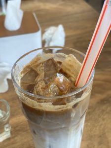 
A glass of iced latte with visible ice cubes and layers of dark coffee and creamy milk.
