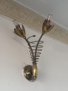 A vintage wall lamp designed to resemble a flower with two metallic petals holding light bulbs.