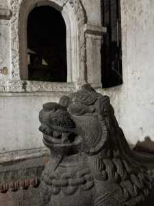 A stone statue of a mythical creature, resembling a lion, with intricate carvings on its body and face