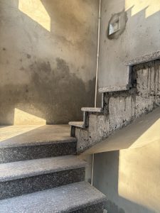 A staircase with a mix of granite steps and unfinished concrete walls