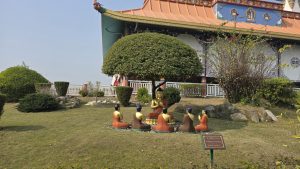 
A serene garden scene featuring a golden Buddha statue sitting underneath a rounded tree.