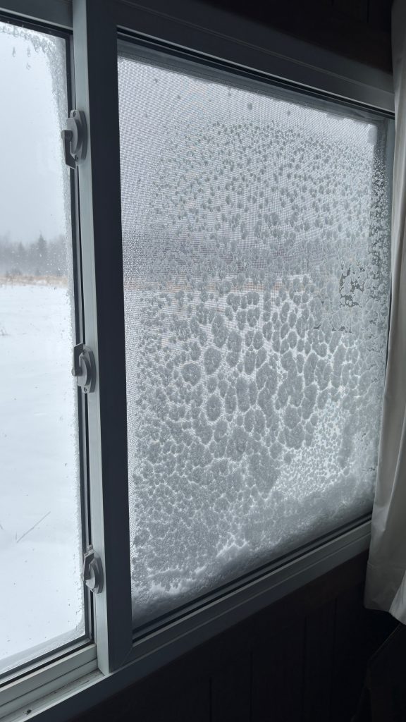 A window with the screen encrusted with snow and ice.