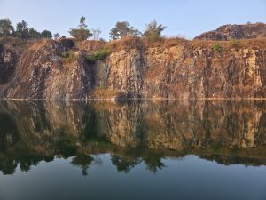 A rocky cliff rising from a calm body of water