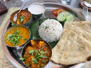 A vegetarian thali includes roti, vegetables, salad, rice, and lentil soup.
