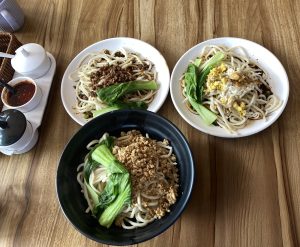 
Three plates of noodles are arranged on a wooden table. 