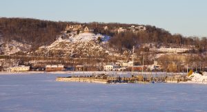 An iced over Peekskill Bay with the sailing club docks in the foreground and the Abbey up on the hill in the background.