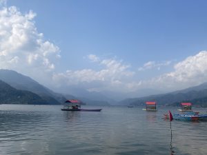 
A serene lake view with calm waters reflecting the blue sky and fluffy white clouds.