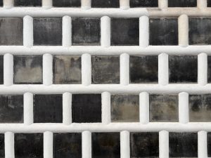 Traditional Japanese "namako" wall with raised white plaster joints and dark tiles forming a clean geometric grid.