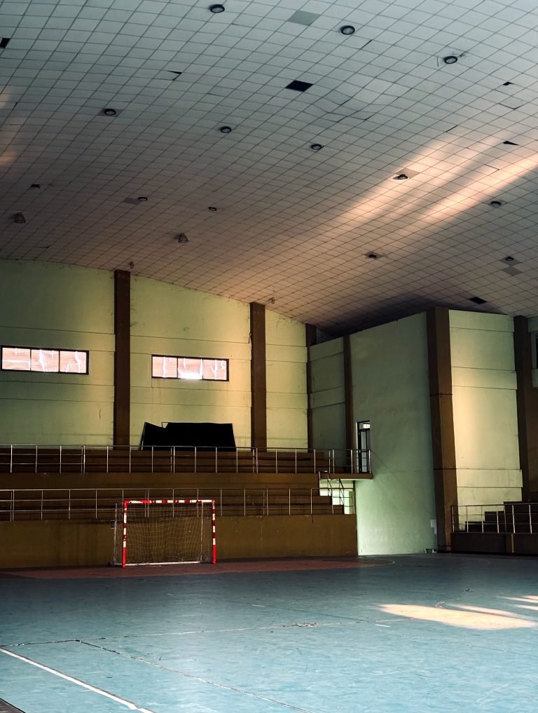An indoor Futsal sports hall with a high ceiling and windows that let in natural light.