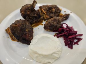 Spiced Shawaya Chicken, served with a white dip and pickled vegetables, simply and neatly plated in Kozhikode, Kerala. 