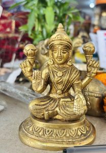 A detailed golden statue of a deity seated in a meditative pose with four arms, each holding various symbolic objects.