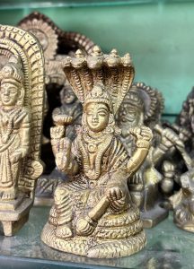 A detailed brass statue of a seated deity with multiple arms, each holding various symbolic items.