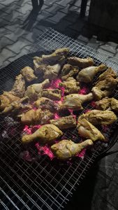 Chicken legs on a metal mesh over hot coals.

