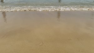 A close-up view of a sandy beach, with gentle waves lapping against the shore.
