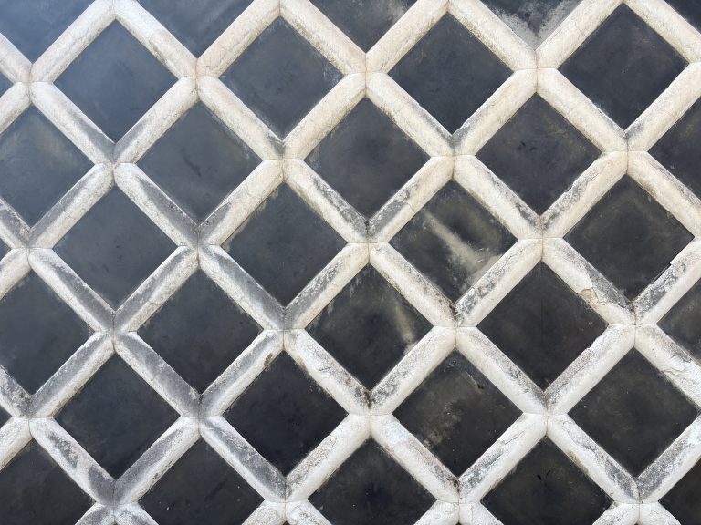 Traditional Japanese “namako” wall featuring raised white plaster lines and dark tiles forming a geometric diamond pattern.