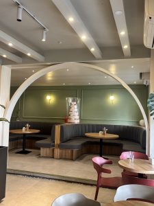 A modern café interior featuring a light green wall with decorative lighting.