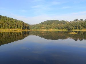 


A calm Maidi lake surrounded by lush green hills under a clear blue sky.