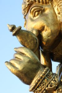 A close-up of a golden statue of God Ganesh, showing a prominent trunk and large ears.