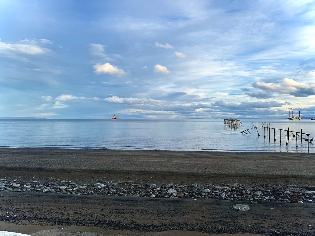 Calm water reflecting the sky along the shoreline at the Strait of Magellan, Punta Arenas, Chile.