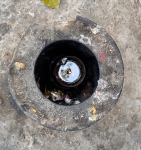 A close-up of a traditional lamp with a wick and liquid inside, placed on a rough surface.