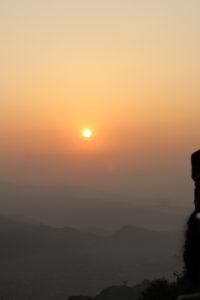 
A serene sunrise view featuring a bright sun setting against a hazy orange and yellow sky