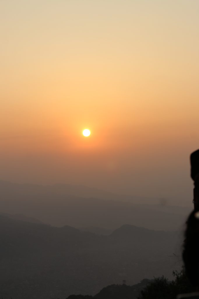 A serene sunrise view featuring a bright sun setting against a hazy orange and yellow sky
