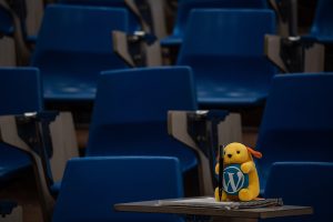 Wapuu in lecture hall taking notes.