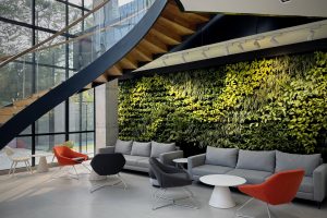 A modern, stylish lounge area featuring a grey sectional sofa and various chairs in orange, black, and white.
