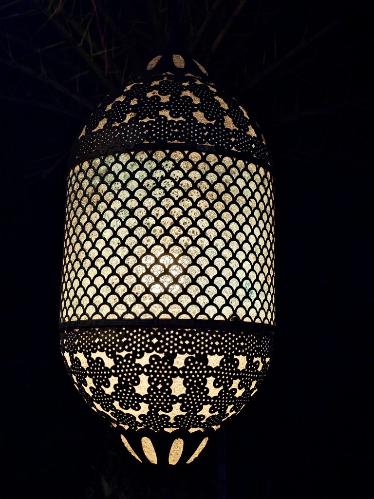 A Moroccan-style metal hanging pendant light with an antique finish and intricate cutwork patterns.
