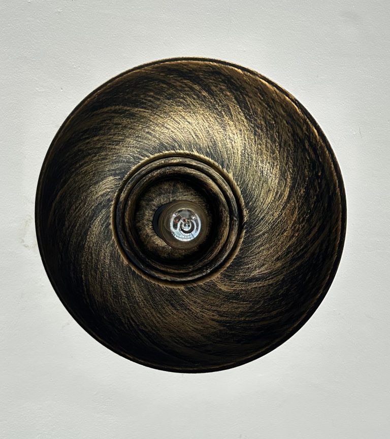 A circular light fixture viewed from directly below, featuring a swirling, textured design that resembles a mix of dark brown and gold tones.