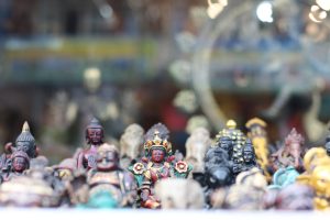 A collection of small, intricately designed figurines representing various deities, including Buddhist and Hindu figures, displayed closely together.