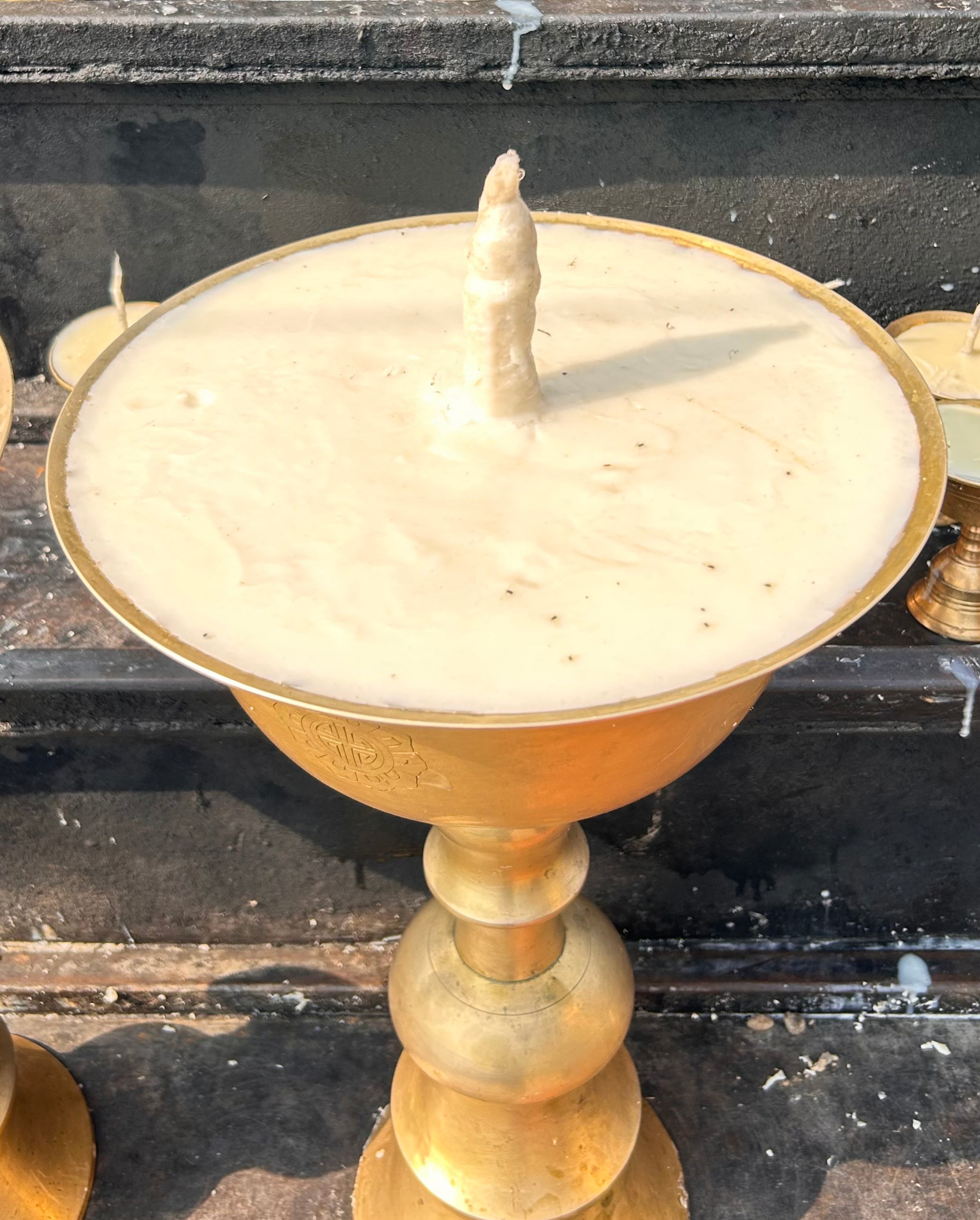 A golden pedestal holds a shallow, circular bowl filled with a creamy, pale substance