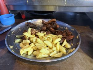 Street fried chips and chicken on a platter, a few cabbages and ketchup