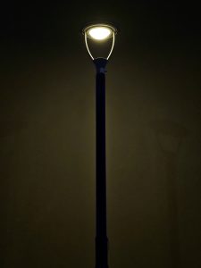 A tall street lamp, glowing softly in the dark night sky in Mankavu, Kozhikode, creates a calm, quiet mood with warm light.
