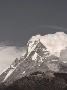 

A dramatic Fishtail mountain peak towers against a backdrop of swirling clouds