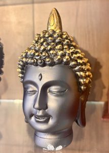 A decorative statue of a Buddha head, characterized by a serene expression, closed eyes, and a slight smile.
