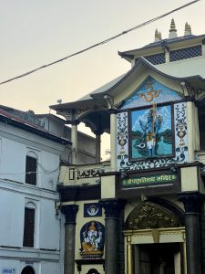 Colorful facade of Pashupati Temple with intricate artwork and a serene blue deity figure.