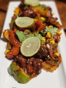 A colourful spicy stir-fry with vegetables, herbs, and lemon slices served on a plate in Kozhikode, Kerala, looking rich, hot, and full of flavour. 