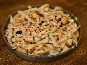 Close-up of cheesy French fries with sauce, chili flakes, paneer, and small toppings in Kozhikode, Kerala, showing the texture and flavour clearly.
