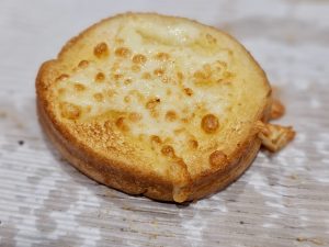 A round slice of toasted Garlic bread topped with melted cheese in Kozhikode, Kerala, golden and crisp on the edges. 
